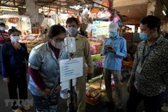 Người dân kiểm tra thân nhiệt trước khi vào chợ để phòng chống dịch COVID-19 tại Lào. (Ảnh: AFP/TTXVN)