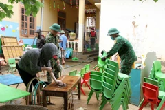 Cán bộ chiến sỹ bộ đội biên phòng Nghệ An cùng giáo viên, phụ huynh học sinh Trường mầm non xã Tà Cạ, huyện Kỳ Sơn, dọn dẹp, vệ sinh, phun tiêu độc khử trùng sẵn sàng đón học sinh trở lại trường sau mưa lũ. (Ảnh: Văn Tý/TTXVN)
