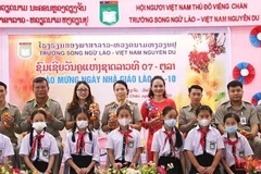 Các em học sinh Trường song ngữ Lào-Việt Nam Nguyễn Du tặng hoa tri ân các thầy, cô giáo nhân Ngày nhà giáo quốc gia Lào. (Ảnh: Hải Tiến) 