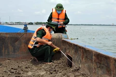 Lực lượng bộ đội biên phòng kiểm tra số lượng cát bị vận chuyển trái phép trên sông. (Ảnh: TTXVN phát)
