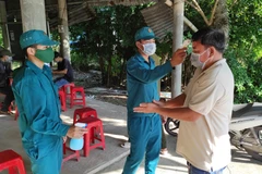 Đo thân nhiệt và hướng dẫn khai báo y tế khi qua các chốt kiểm soát dịch trên tuyến đường bộ. (Ảnh: TTXVN)