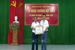 Ông Nguyễn Văn Trung (phải) nhận Bằng khen của Chủ tịch UBND tỉnh Nghệ An vì hành động dũng cảm cứu người đuối nước. (Nguồn:Tá Chuyên/TTXVN) 