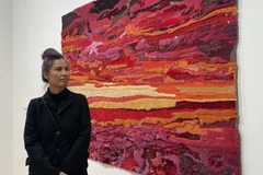 Nghệ sỹ trẻ Tia-Thủy Nguyễn với một trong những tác phẩm trong bộ sưu tập "Lấp lánh giữa bao la." (Ảnh: Nguyễn Thu Hà/TTXVN) 