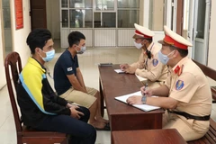 Lực lượng chức năng làm việc với lái xe và chủ hàng. (Ảnh: Đức Phương - TTXVN)