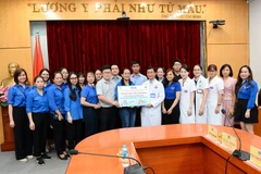 Đoàn thanh niên TTXVN trao bảng tượng trưng 70 suất quà và hơn 300 đầu sách cho Khoa Nhi - Bệnh viện K (cơ sở 3). (Ảnh: Minh Đức/TTXVN) 