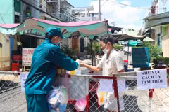 Phát thực phẩm, nhu yếu phẩm cho người dân trong khu vực bị phong tỏa tại con hẻm trên đường Đoàn Phú Tứ, phường An Lạc A, TP.Hồ Chí Minh. (Ảnh: TTXVN phát)