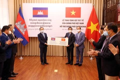 Thứ trưởng Bộ Y tế Trần Văn Thuấn và Thứ trưởng Bộ Ngoại giao Nguyễn Quốc Dũng trao tượng trưng vật tư y tế của Chính phủ Việt Nam cho Đại sứ Campuchia tại Việt Nam Chay Navuth. (Ảnh: Phạm Kiên - TTXVN)