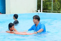 Giáo viên hướng dẫn kỹ thuật bơi cho thiếu nhi. (Ảnh: Lê Thúy Hằng/TTXVN)