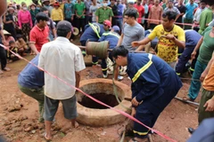 Lực lượng cứu hộ phối hợp với người dân trục vớt thi thể 2 nạn nhân. (Ảnh: TTXVN phát)
