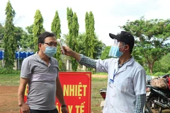 Đo thân nhiệt cho người vào tỉnh Đắk Lắk tại chốt kiểm soát phòng, chống dịch COVID-19 trên Quốc lộ 14. (Ảnh: Tuấn Anh – TTXVN)