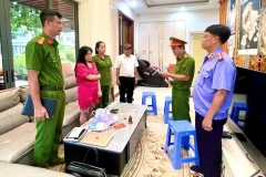 Cơ quan cảnh sát điều tra đọc lệnh khám xét nơi làm việc của Đỗ Thị Thu Trang (áo đỏ). (Ảnh: TTXVN phát)
