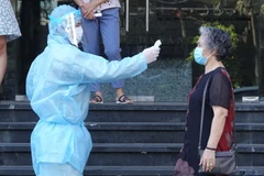 Nhân viên Tổ bầu cử kiểm tra thân nhiệt cử tri ở khu cách ly. (Ảnh: Văn Dũng - TTXVN)