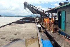 Cảnh sát với súng AK kiểm tra tang vật trên các tàu "cát tặc." (Nguồn: Báo mới)