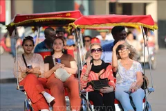 Du khách quốc tế trên xe xích lô đi tham quan phố cổ, Hồ Hoàn Kiếm. (Ảnh: Thanh Tùng/TTXVN)