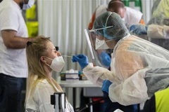 Nhân viên y tế lấy mẫu xét nghiệm COVID-19 cho người dân tại London (Ảnh: AFP/TTXVN)