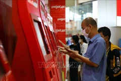 Hành khách làm thủ tục trực tuyến tại kios của Vietjet tại sân bay Nội Bài. (Ảnh: Huy Hùng/TTXVN)