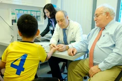 Bác sỹ Stéphane Guero (giữa) khám cho một bệnh nhi bị dị dạng ngón tay. (Ảnh: TTXVN phát)