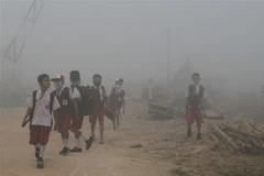 Học sinh tới trường trong điều kiện khói mù dày đặc tại Palembang, Indonesia, ngày 14/10/2019. (Ảnh: AFP/ TTXVN)