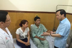 Bộ trưởng Đào Ngọc Dung hỏi thăm sức khỏe Thiếu tá phi công Nguyễn Hữu Cường. (Ảnh: Hồng Kiều/Vietnam+)