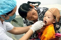 Điều trị bệnh tay chân miệng cho trẻ. (Ảnh: Dương Ngọc/TTXVN)