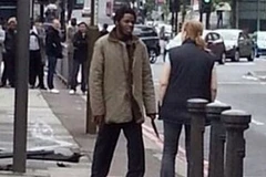 Một trong hai kẻ giết người cầm dao nói với một phụ nữ đi ngang qua. (Nguồn: Guardian) 