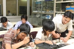 Giáo viên hướng dẫn thực hành sửa chữa điện thoại. (Ảnh: Hà Thái/TTXVN).