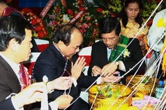 Đại sứ Lào tại Việt Nam buộc chỉ lên cổ tay Phó Thủ tướng Nguyễn Xuân Phúc tại lễ buộc chỉ cổ tay truyền thống của nhân dân các bộ tộc Lào. (Ảnh: Doãn Tấn/TTXVN)