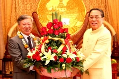 Đại sứ Nguyễn Mạnh Hùng chuyển lẵng hoa của Tổng Bí thư Nguyễn Phú Trọng tới Tổng Bí thư, Chủ tịch nước Lào Chummaly Saynhasone. (Ảnh: Hoàng Chương/Vietnam+)