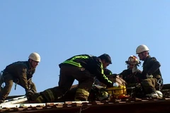 Lực lượng cứu hộ đang tìm cách đưa tên đạo chích ra khỏi ống khói.(Nguồn: Internet)