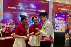 Người tiêu dùng hào hứng với ứng dụng thanh toán điện tử không dùng tiền mặt tại Sự kiện. (Ảnh: Phương Anh/TTXVN)