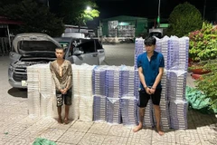 Hai đối tượng vận chuyển 15.000 bao thuốc lá ngoại nhập lậu bị bắt giữ cùng tang vật. (Ảnh: TTXVN phát)