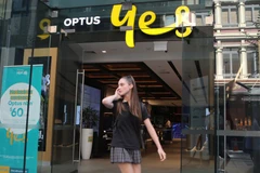 Một phụ nữ sử dụng điện thoại di động khi đi ngang qua cửa hàng Optus ở Sydney, Australia. (Nguồn: Reuters)
