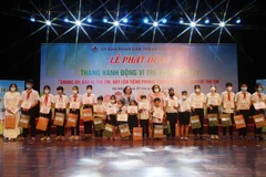 Các em học sinh vượt khó học giỏi và trẻ có hoàn cảnh đặc biệt khó khăn được nhận học bổng và quà tại buổi lễ. (Ảnh: Trần Lê Lâm/TTXVN)