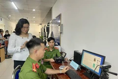 Lực lượng công an hướng dẫn cho người dân sử dụng dịch vụ công trực tuyến. (Ảnh: Huyền Trang/TTXVN)