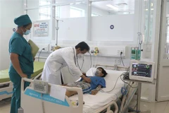 Bác sỹ thăm khám cho bệnh nhi bị sốc do sốt xuất huyết nặng. (Ảnh: Lê Thúy Hằng/TTXVN)