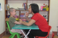 Giáo viên can thiệp, trị liệu và hỗ trợ hòa nhập cho trẻ tự kỷ ở Trung tâm jỗ trợ phát triển giáo dục hòa nhập Thiên thần nhỏ, Ninh Bình . (Ảnh: Thùy Dung/TTXVN)