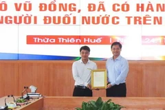 Trao thư khen của Chủ tịch nước Nguyễn Xuân Phúc cho anh Tô Vũ Đồng. (Ảnh: Tường Vi/TTXVN)