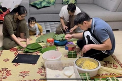 Một gia đình Việt kiều ở Vitré quây quần gói bánh chưng. (Ảnh Thu Hà/TTXVN)