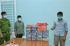 Đối tượng Phạm Nhật Hồng Đăng (bên phải) cùng số tang vật thu giữ 18 hộp pháo nổ, trọng lượng 26kg. (Ảnh: TTXVN phát)