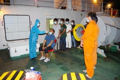 Lực lượng y tế tiến hành test COVID-19 cho 8 người nước ngoài bị nạn trên biển. (Ảnh: TTXVN phát)