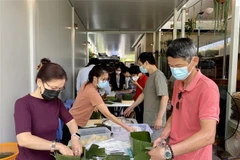 Các thành viên trong tổ gói bánh chưng gây quỹ hỗ trợ trẻ em nghèo tại Việt Nam. (Ảnh: Nguyễn Minh/TTXVN)