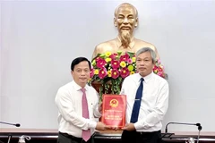 Phó Chủ tịch Thường trực UBND tỉnh Bình Định Nguyễn Tuấn Thanh (trái) trao quyết định cho ông Đặng Vĩnh Sơn. (Ảnh: Nguyên Linh/TTXVN)