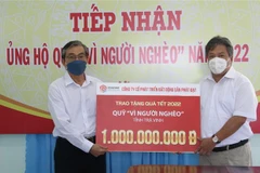 Chủ tịch Ủy ban Mặt trận Tổ quốc Việt Nam tỉnh Trà Vinh Nguyễn Văn Triết (trái) tiếp nhận 1 tỷ đồng hỗ trợ quà Tết hộ nghèo từ Công ty Cổ phần Phát triển Bất động sản Phát Đạt. (Ảnh: Thanh Hòa/TTXVN)