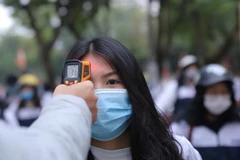 Kiểm tra thân nhiệt của học sinh khi đến trường. (Ảnh: Hoàng Hiếu/TTXVN)