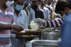 Người dân nhận thức ăn từ thiện trong bối cảnh dịch COVID-19 hoành hành tại Hyderabad, Ấn Độ. (Ảnh: AFP/TTXVN)