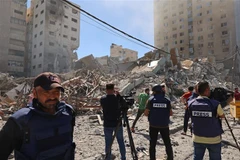 Các phóng viên tại hiện trường đổ nát của Toà tháp Jala, nơi đặt văn phòng một số hãng truyền thông quốc tế, sau khi máy bay Israel oanh tạc Dải Gaza, ngày 15/5. (Ảnh: AFP/TTXVN)