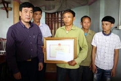 Ông Ngũ Duy Anh, Vụ trưởng Vụ Công tác học sinh sinh viên, Bộ Giáo dục và Đào tạo trao Bằng khen truy tặng em Nguyễn Văn Thao tới người thân trong gia đình. (Ảnh: Thu Hằng/TTXVN)