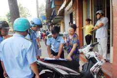 Lực lượng chức năng tiến hành tháo dỡ nhiều trường hợp nhà dân dựng mái che, biển hiệu chiếm vỉa hè đường Nguyễn Đình Chiểu (phường Đa Kao, quận 1). (Ảnh: Mạnh Linh/TTXVN)