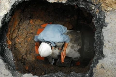 Nhân viên Công ty Thoát nước đô thị xử lý một hố tử thần (Ảnh: Mạnh Linh/TTXVN)