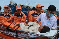 Lực lượng cứu nạn cùng y, bác sỹ hỗ trợ đưa ngư dân đi cấp cứu. (Ảnh: Nguyên Lý/TTXVN)
